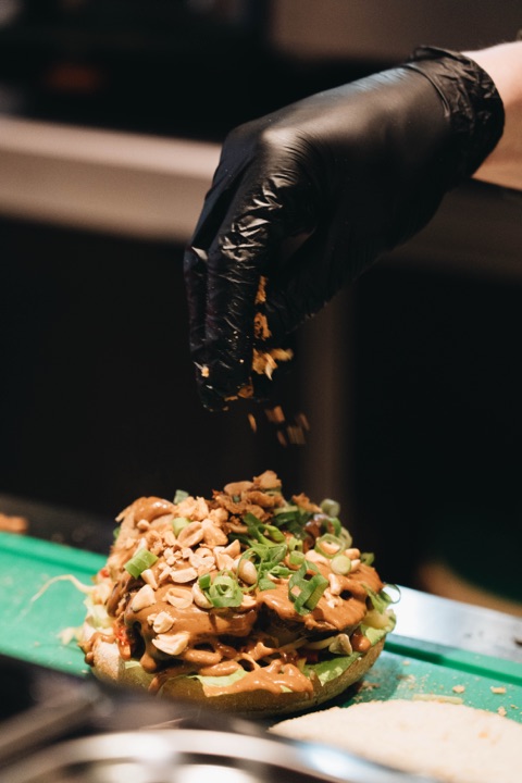 Verse toppings worden over de gehaktbal gestrooid in de open keuken aan de Kinkerstraat